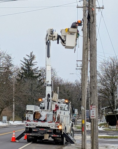 A utility crew splices fiber while suspended in air by bucket truck
