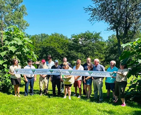 A dozen locals stand behind ribbon at Northwest Fiberworx ribbon cutting ceremony.