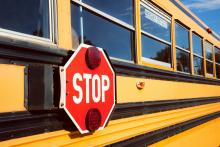 Side of school bus with stop sign affixed to side of bus