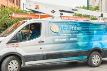 A utility worker sits behind the wheel of a Traverse City utility van advertising its fiber service