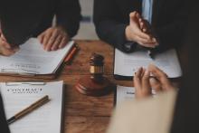 A group of people sit at a desk reviewing legal documents but we can only see their hands